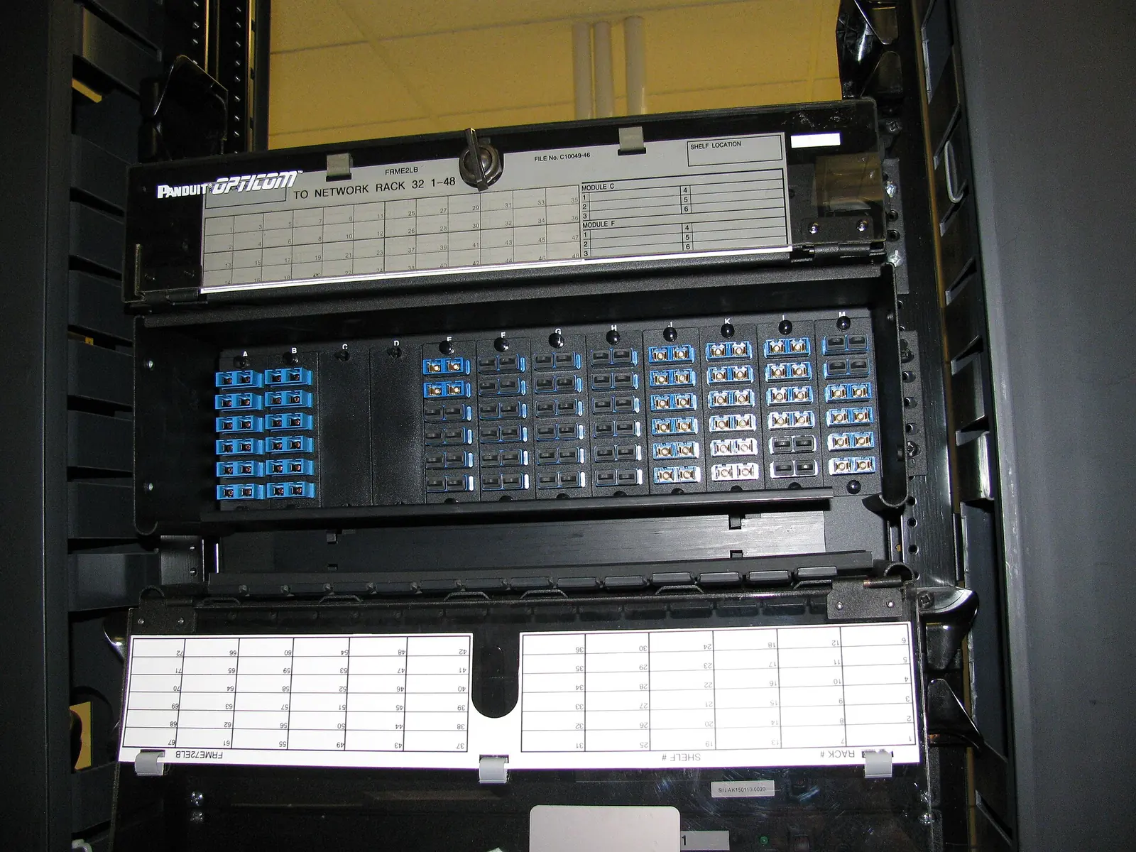 Fibre patch panels with rows of blue connectors inside a network rack